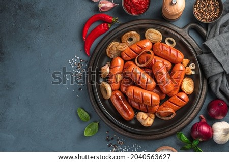 Fried sausages with basil, onion, garlic on a dark background. Fast food. Top view, space for copying. Royalty-Free Stock Photo #2040563627