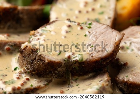 Roast Pork Tenderloin in mustard gravy with vegetables and potato wedges. Royalty-Free Stock Photo #2040582119