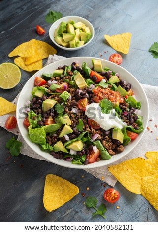 Beef Taco salad with romaine lettuce, avocado, tomato salsa, black bean and tortilla chips. Mexican healthy food.