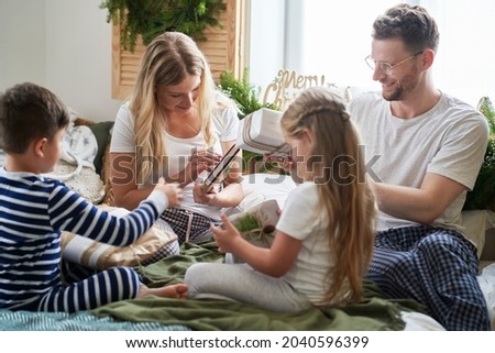 Family opening the Christmas presents in bed