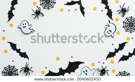 Happy Halloween holiday concept. Frame made of halloween decorations, ghosts, bats, spiders on white background. Flat lay, top view, copy space.