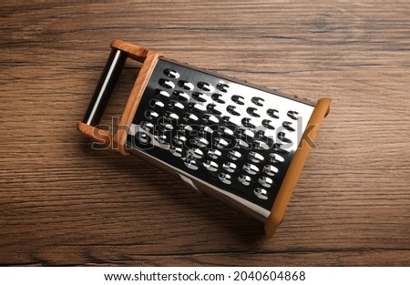 Modern grater on wooden table, top view