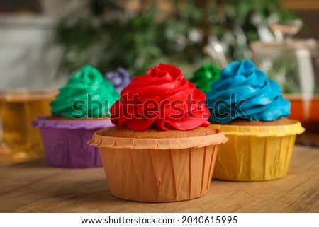 Delicious cupcakes with colorful cream on wooden table, closeup