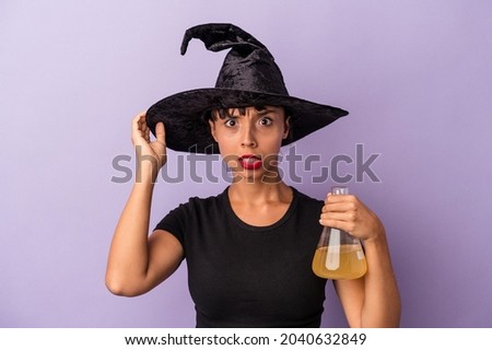 Young mixed race woman disguised as a witch holding potion isolated on purple background  being shocked, she has remembered important meeting.