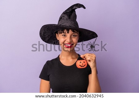 Young mixed race woman disguised as a witch isolated on purple background  happy, smiling and cheerful.
