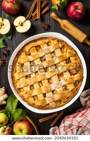 Apple pie with ginger and cinnamon at dark wooden table.