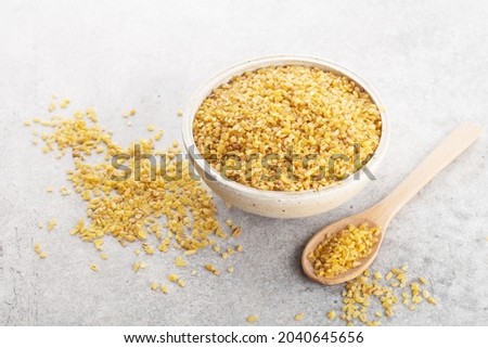 bulgur grits in a bowl on a napkin, gray background, space for text, horizontally Royalty-Free Stock Photo #2040645656