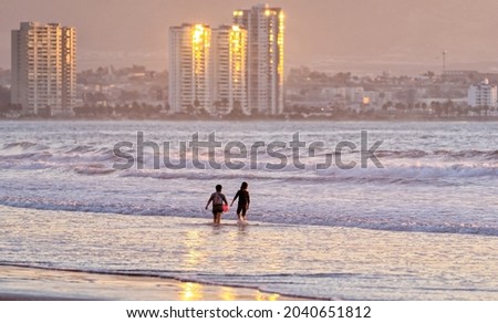 two children playing in the ocean at sunset in La Serena