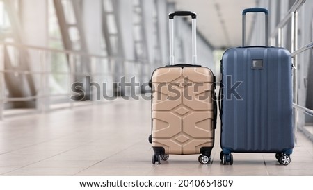 Two stylish suitcases standing in empty airport hall, unrecognizable traveller's luggage waiting in terminal, creative banner for air travels or vacation trip, panorama with copy space Royalty-Free Stock Photo #2040654809