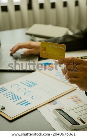 Businessman holding credit card and right hand typing on keyboard to order online and pay bills online.