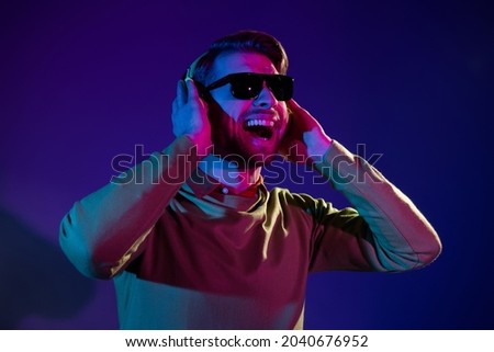 Photo of attractive young man wear headset sunglass good mood dj isolated on gradient neon background