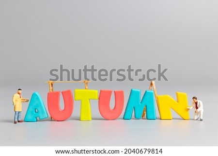Miniature people worker team painting of Autumn with place for text on grey background, Hello Autumn concept
