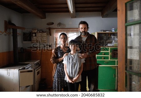 Portrait of poor mature couple with small daughter indoors at home, poverty concept. Royalty-Free Stock Photo #2040685832