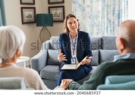 Social worker, talking to old man and woman for insurance plans on retirement. Happy supporter with senior people during a home consultation: counseling and psychological session at home. Royalty-Free Stock Photo #2040685937