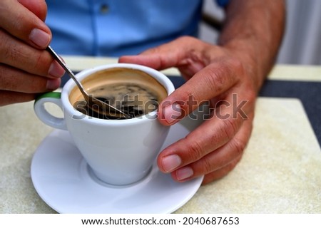 Hand holding a cup of coffe  Man in blue shirt