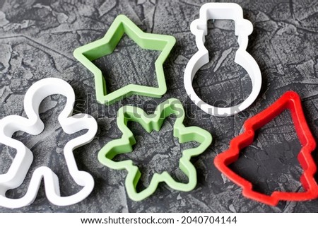 Molds for cutting out Christmas cookies in the form of a snowman, a star, a man, a snowflake and a Christmas tree on a black background. Sweets for the New Year.