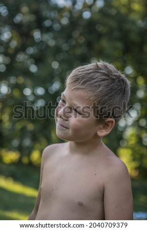 Funny baby boy isolated on a background of green trees. Smiling child boy