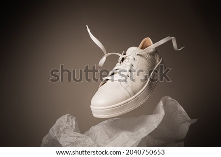 Fashion - white leather unisex sneakers shoe. Footwear levitating on the gray background. Layout with free copy (text) space. Royalty-Free Stock Photo #2040750653