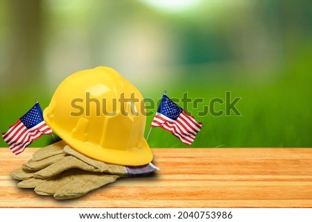 Handsome man holding US Flag and construction helmet. Labor and employment concept