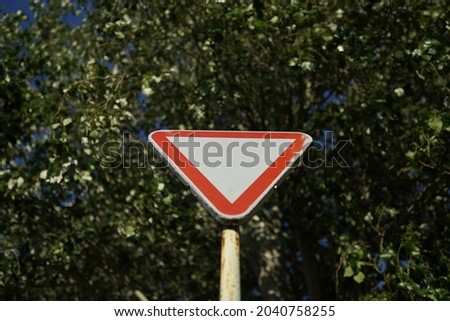 A blank triangle warning road sign against the trees