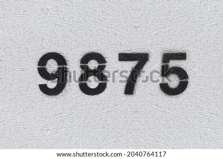 Black Number 9875 on the white wall. Spray paint. Number nine thousand eight hundred and seventy five.