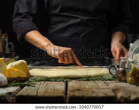 The chef prepares Italian focaccia bread for baking. Ingredients. A classic Italian recipe. Wooden texture. Close-up. Restaurant, hotel, home cooking, bakery, Italian cuisine.