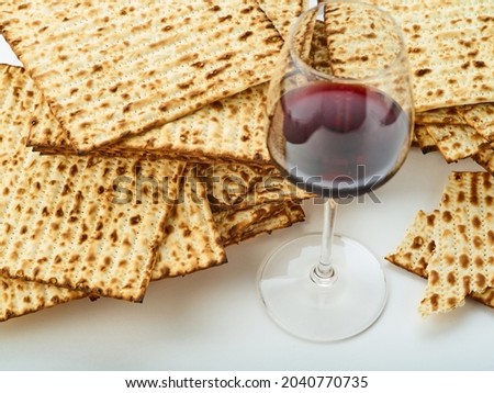 Stacks of matzah-Jewish Passover bread and red wine in a glass. White background. Low angle view. Jewish Passover, religion, Judaism, traditions, rituals, synagogue, Torah.