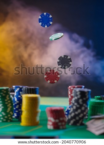 Casino. Gambling house. Chips. Levitation. Many chips are also stacked on the green gambling table. In the background there is a beautiful multi-colored smoke. Gambling, gambling business.
