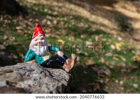 gnome lying on a rock surrounded by autumn ocher leaves. Horizontal picture