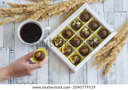 Handmade coffee chocolates in a porcelain cup of dried flowers on a gray wooden background. Sweets still life photo.