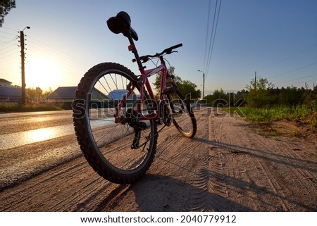 Bicycle silhouette at the sunrise dirt road in the countryside. Idea and concept of physical activity and healthy lifestyle.