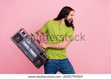 Portrait of attractive cheerful funky wavy-haired guy carrying player having fun isolated over pink pastel color background
