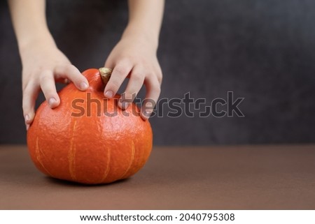 Close up of pumpkin for Halloween and children's hands. Halloween, decoration and theme party concept