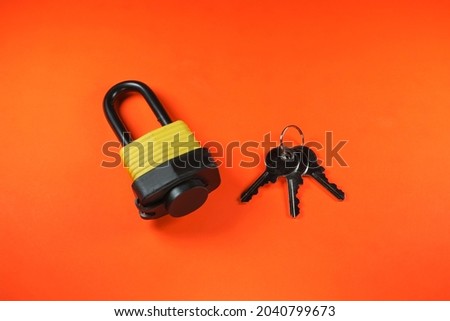 Yellow and black waterproof padlock with key on orange background isolated 