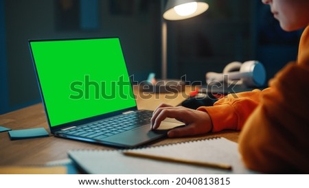Smart Young Boy Researching Homework on Laptop Computer with Green Screen Display. Teenager Browsing Educational Research, Studying School Material.