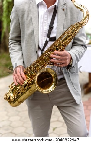 Saxophonist with saxophone prepares to perform at the holiday. Jazz concert on open air