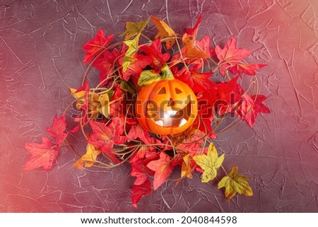 Laughing luminous pumpkin Jack-o-lantern in maple leaves on glowing neon textured background. Halloween poster, postcard. Halloween sale ready-made template.