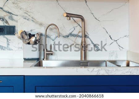 New sink and modern tap in stylish kitchen. Luxury new kitchen with marble tiled backsplash. Modern kitchen interior. Clean kitchen sink, close up. Royalty-Free Stock Photo #2040866618