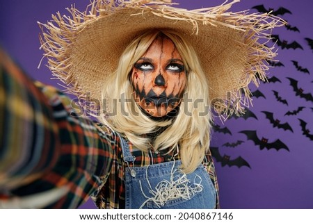 Close up young woman with Halloween makeup mask in straw hat scarecrow costume do selfie shot pov mobile phone look overhead isolated on plain dark purple background studio Celebration party concept