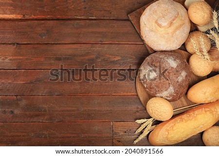 Freshly baked homemade sourdough bread with crispy crust and ears of rye and wheat on an old wooden background with place for text, modern bakery concept, top view, healthy natural food