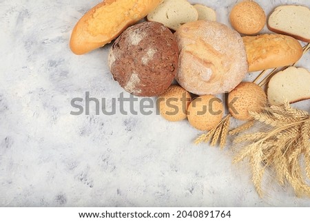 Freshly baked homemade sourdough bread with crispy crust and ears of rye and wheat on an old concrete background with place for text, modern bakery concept, healthy natural food, selective focus
