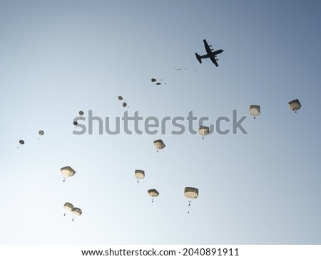United States Army Soldiers and Paratroopers descending in the sky, from an Air Force C-130 military aircraft during an Airborne Operation. Royalty-Free Stock Photo #2040891911