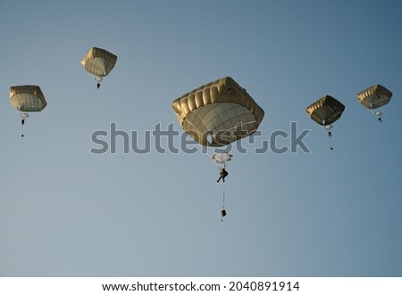 United States Army Soldiers and Paratroopers descending in the sky, from an Air Force C-130 military aircraft during an Airborne Operation. Royalty-Free Stock Photo #2040891914
