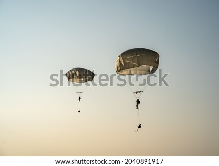 United States Army Soldiers and Paratroopers descending in the sky, from an Air Force C-130 military aircraft during an Airborne Operation. Royalty-Free Stock Photo #2040891917