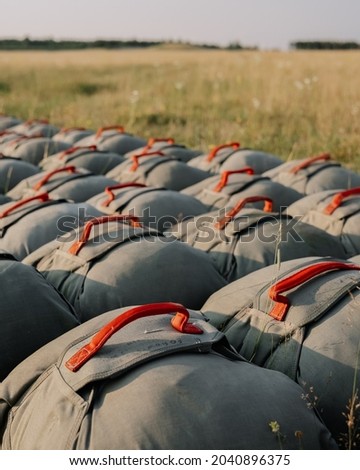 United States Army T-11 Reserve Parachutes lay on the ground on a military drop zone in Germany.  Royalty-Free Stock Photo #2040896375