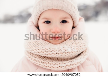 Portrait of a girl playing in the snow during a winter walk and playing snowballs, rolling and skating in the snow