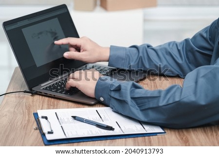 A man use laptop check part for service of car and pen the white paper clip board file on table car service in office concept