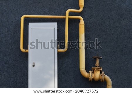 Gas meter box with pipes on grunge grey background. Outdoor gas equipment.