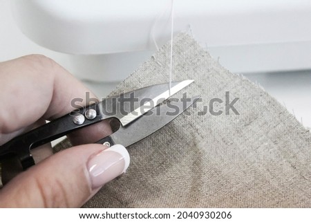 Sewing process. The hand cuts the thread on the fabric.