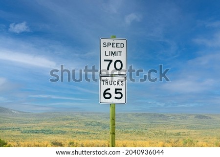 Seventy mph speed limit. Trucks 65 sign on wooden post. Speed zone traffic sign against desert landscape and beautiful blue sky.